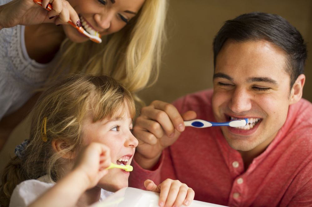 Photo of parents brushing their teeth with a young child